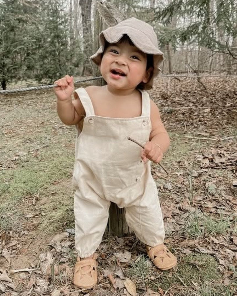 Smiling toddler standing outdoors in leather moccasins