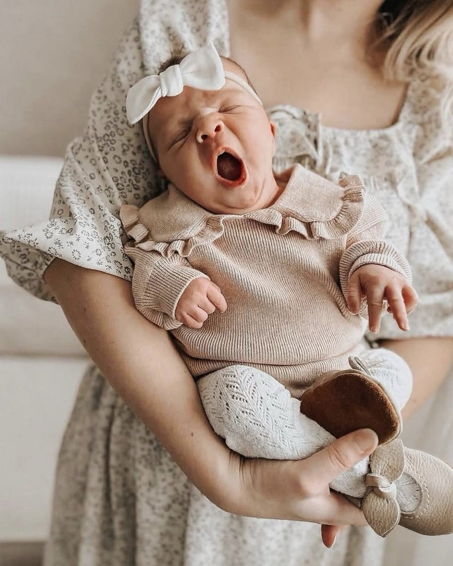 Newborn baby held by mom, wearing soft leather baby shoes