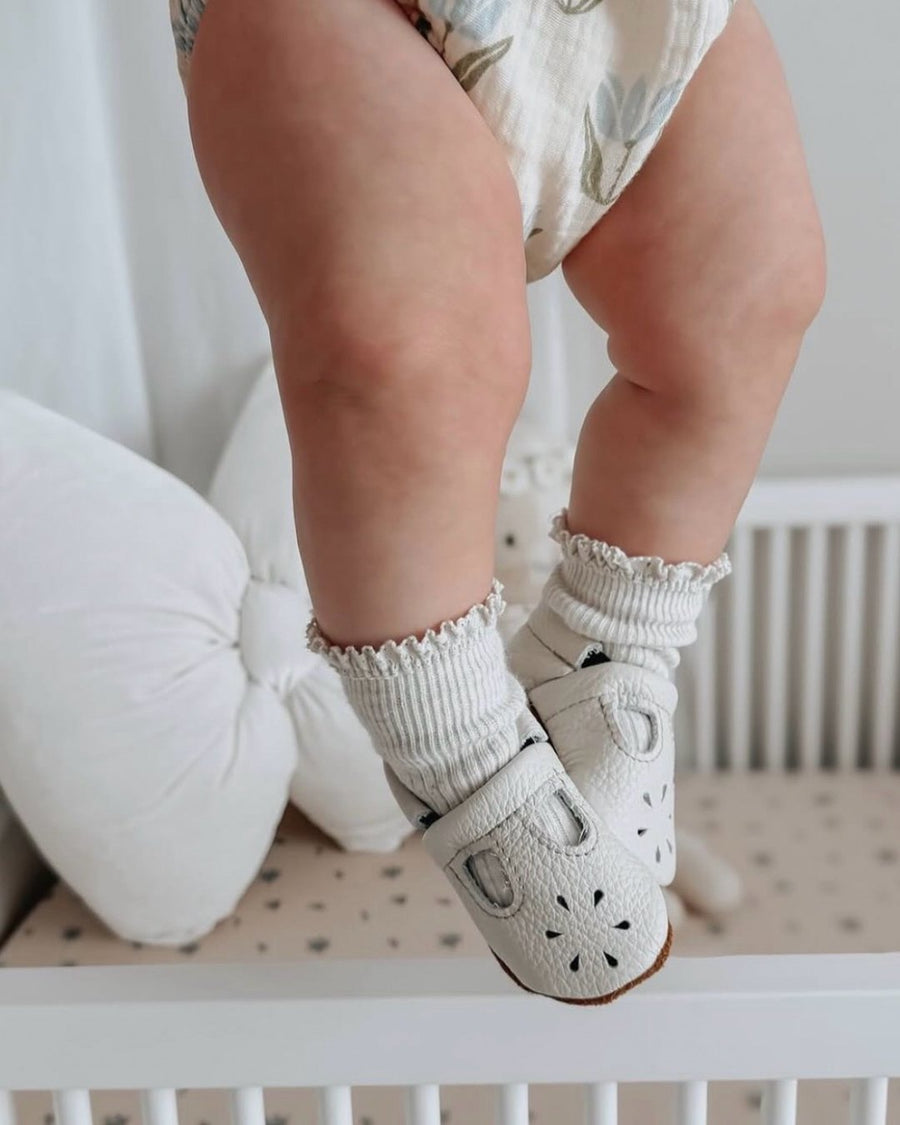 Baby standing in white leather Mary Jane shoes